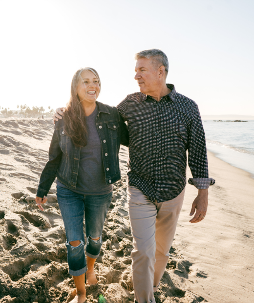 Elderly happy couple walking on beach.